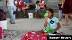 Una niña migrante venezolana lleva su comida al interior de un coliseo donde está instalado un campamento temporal, luego de huir de su país por operaciones militares, según la agencia colombiana de migración, en Arauquita, el 27 de marzo de 2021.