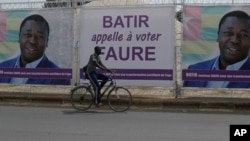 A man rides a bicycle past election posters of Togo's Incumbent President Faure Gnassingbe, Presidential Candidate of Union for the Republic, on the street in Lome, Togo, Feb. 21, 2020. 