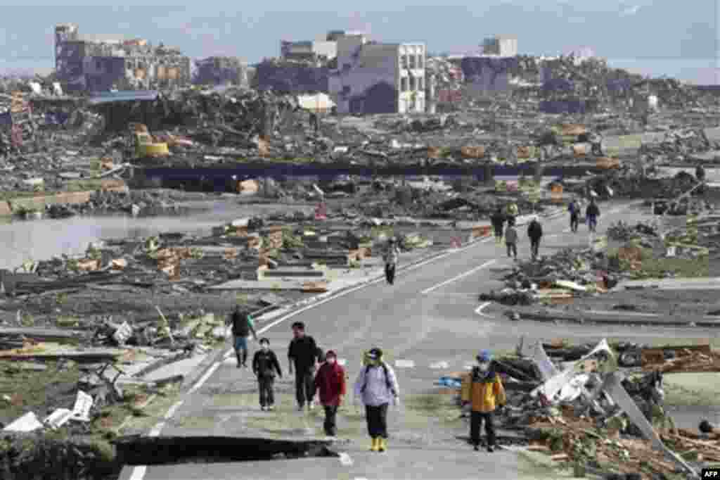 People walk a road between the rubble of destroyed buildings in Minamisanriku town, Miyagi Prefecture, northern Japan, Monday, March 14, 2011, three days after a powerful earthquake-triggered tsunami hit the country's east coast. (AP Photo/The Yomiuri Shi