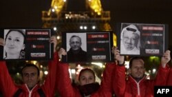 People hold portraits of killed journalists in front of the Eiffel Tower during an event organised by the Reporters Without Borders