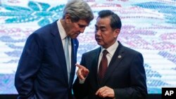 U.S. Secretary of State John Kerry, left, and Chinese Foreign Minister Wang Yi chat after a group photo session before the East Asia Summit Foreign Ministers' Meeting in Kuala Lumpur, Malaysia, Aug. 6, 2015. 