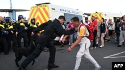 FILE - A police officer restrains a protester during a demonstration called by far-right activists in Weymouth, on the southwest coast of England where the Bibby Stockholm migrant accommodation barge is moored, on Aug. 4, 2024.