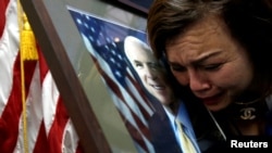 U.S. Vietnam-born citizen Mai Tran mourns near a portrait of U.S. Senator John McCain (R-AZ) after she paid respect to him at the U.S. embassy in Hanoi, Vietnam, Aug. 27, 2018. (REUTERS/Kham)