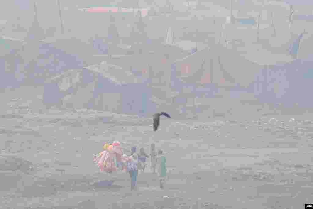 A vendor selling balloons looks for customers in a slum area amid heavy smoggy conditions in Lahore, Pakistan.