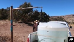 FILE -- Phillip Yazzie fills a water drum in the back of his pickup truck to be filled in Teesto, Ariz., on the Navajo Nation, on Feb. 11, 2021. 