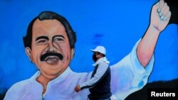 Un hombre, con una mascarilla para protegerse contra la enfermedad del coronavirus, camina junto a un mural con la imagen del presidente de Nicaragua, Daniel Ortega, en Managua, el 30 de marzo de 2020.