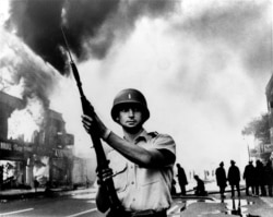 FILE - In this July 1967 file photo, a National Guardsman stands at a Detroit intersection during riots in the city.