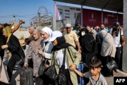 Orang-orang berjalan melewati gerbang saat memasuki perbatasan Rafah ke Mesir di Jalur Gaza selatan, 1 November 2023. (Muhammad ABED/AFP)