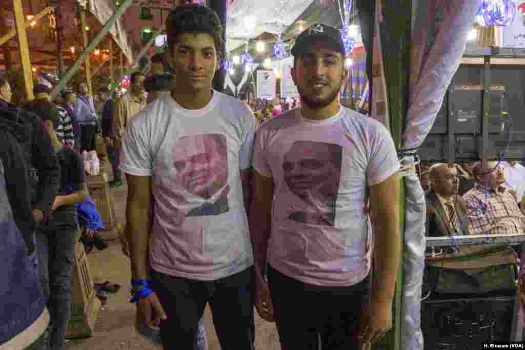Amru Adel, left, and Mohamed Reda, right, wear T-shirts with President Abdel-Fattah el-Sissi&rsquo;s face during a rally in Old Cairo in support of el-Sissi for a second term, March 19, 2018.