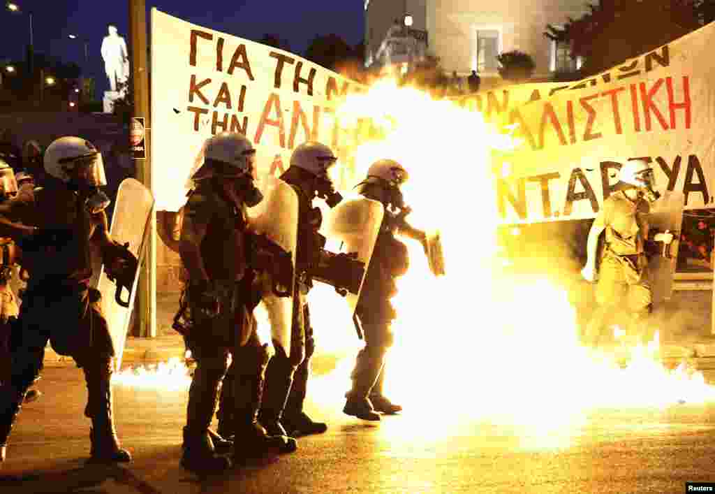 Riot police are surrounded by flames from petrol bombs thrown by a small group of anti-establishment demonstrators in front of parliament in Athens, July 15, 2015.