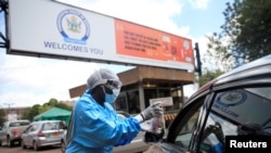 FILE - A health worker screens and sanitizes visitors to prevent the spread of coronavirus disease (COVID-19) outside a hospital in Harare, Zimbabwe, March 26, 2020. 