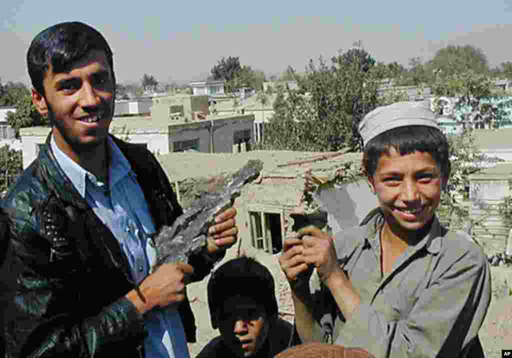 Mohammed Anwar, left, and an unidentifieded boy in Kabul, Afghanistan, display pieces of shrapnel from bombs dropped on October 8, 2001. (AP)