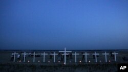 People gather near 11 crosses for the workers who died in the Deepwater Horizon oil rig explosion.