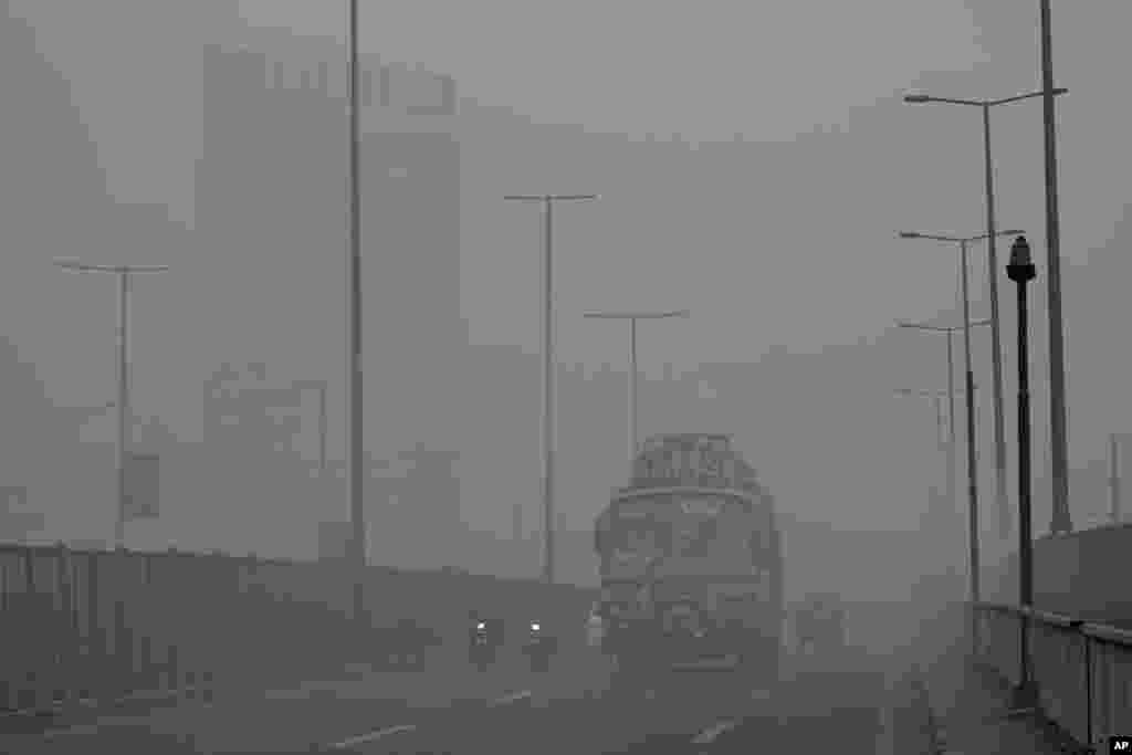 Vehicles move slowly on a road as smog is seen in Lahore in Pakistan.