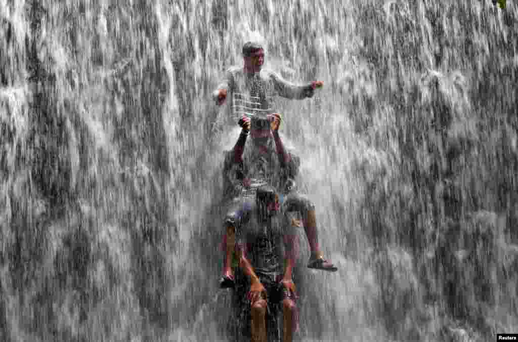 Boys play under an overflowing dam along Powai Lake after heavy rains in Mumbai, India.