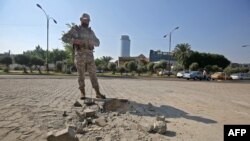 A member of the Iraqi security forces inspects the damage outside the Zawraa park in the capital Baghdad, Nov. 18, 2020, after volley of rockets slammed into the Iraqi capital breaking a month-long truce on attacks against the U.S. embassy.