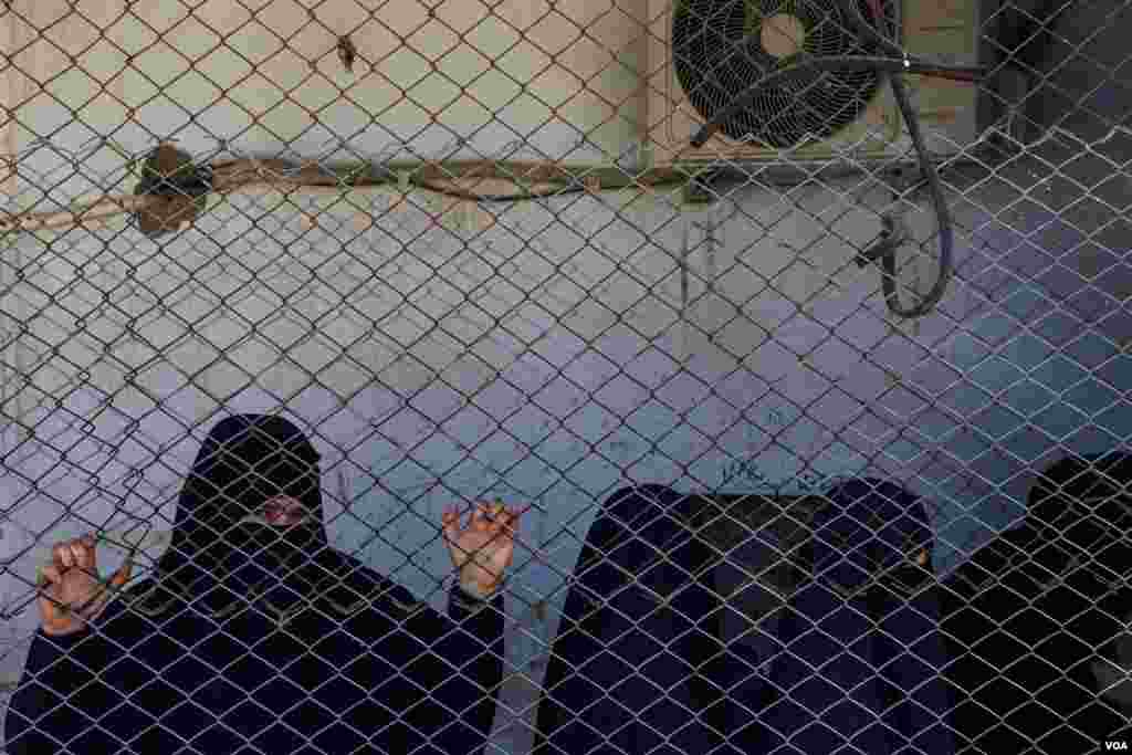 A detainee in Roj Camp watches shoppers in the market area of the detention facility in Northeast Syria, on Oct. 13, 2024. (Diego Baravelli/VOA) 