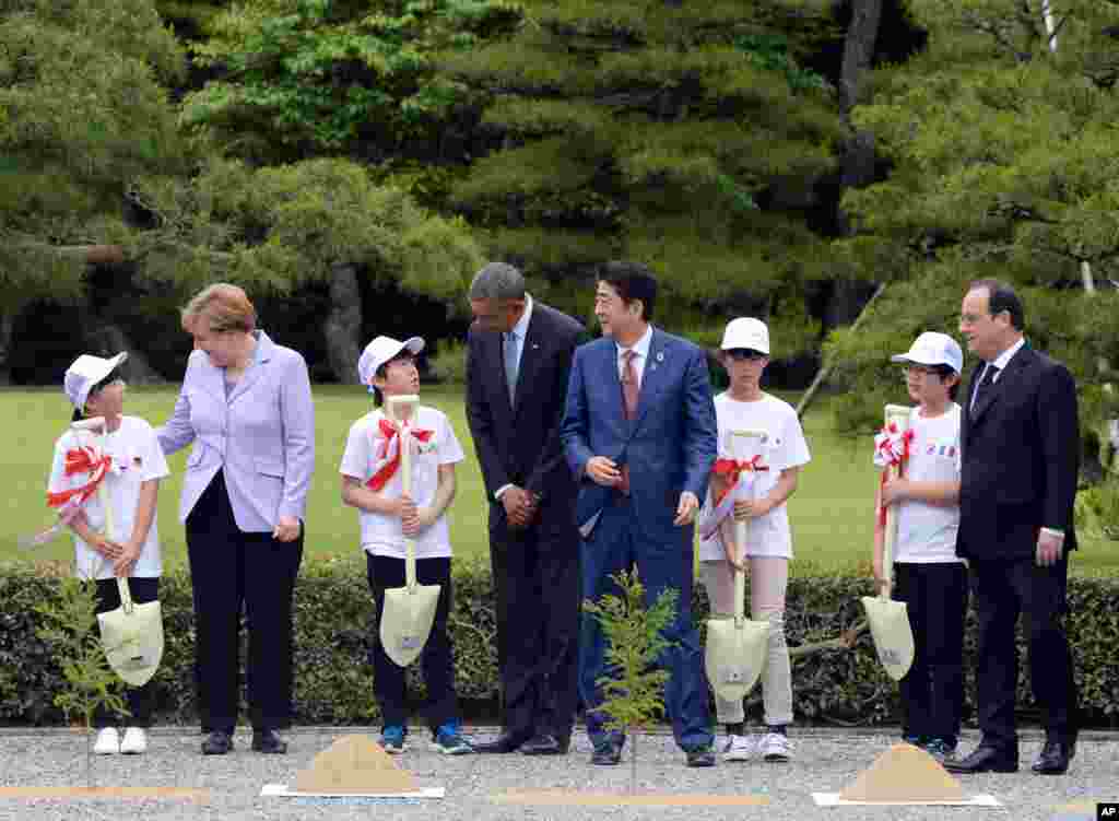 Kanselir Jerman Angela Merkel (kedua dari kiri) dan Presiden AS Barack Obama berbincang dengan anak-anak yang membawakan mereka sekop dalam upacara penanaman pohon saat mengunjungi kuil Ise Jingu di Ise, prefektur Mie, Jepang (26/5).&nbsp;