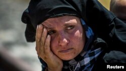 A woman reacts as she rests from walking back to Tel Abyad town, Raqqa governorate, after fleeing Maskana town in the Aleppo countryside June 16, 2015. With a string of victories over Islamic State, Syria's Kurds are proving themselves an ever more depend