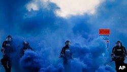 Police in riot gear walk through a cloud of blue smoke as they advance on protesters near the Minneapolis 5th Precinct, May 30, 2020, in Minneapolis. 