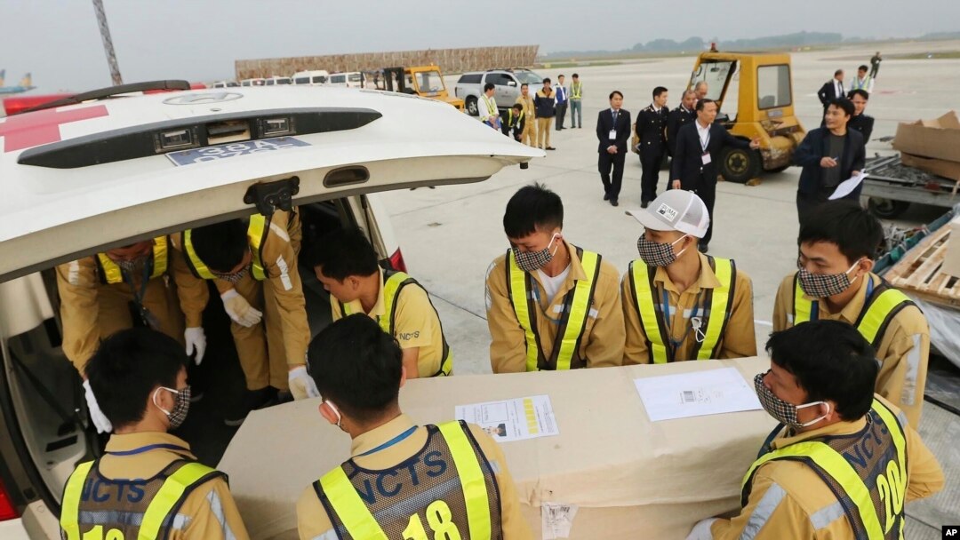 Airport personnel load a coffin into an ambulance at the Noi Bai airport, Nov. 27, 2019 in Hanoi, Vietnam. The bodies of 16 of the 39 Vietnamese found dead in a truck in Britain last month, have been repatriated to their homeland.