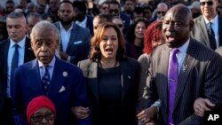 FILE —The Rev. Al Sharpton, Vice President Kamala Harris and Attorney Ben Crump walk and sing across the Edmund Pettus Bridge with others commemorating the 59th anniversary of the Bloody Sunday voting rights march in 1965,March 3, 2024, in Selma, Alabama.