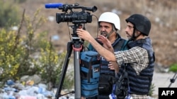 El periodista de AFPTV, Nicolás García Ferrari (izq.), filma con su colega Saleh Hamad en una posición en Ramallah, en la Cisjordania ocupada, el 20 de octubre de 2023, en medio de las batallas en curso entre Israel y el movimiento palestino Hamas.