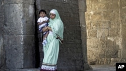 An Indian Muslim woman holds her child as she walks out of Jerusalem's Old City after Friday prayers