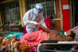 Nepalese paramedics treat a COVID-19 patient outside an emergency ward of a government-run hospital in Kathmandu, Nepal, May 10, 2021.