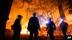 Para pemadam kebakaran di depan sebuah rumah yang terbakar api kebakaran lahan di Boulder Creek, California, 21 Agustus 2020. 