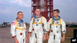 (Foto: Koutwazi LA NAZA). De goch a dwat: Astwonòt veteran Virgil Grissom, Ed White (premye ameriken ki mache nan lespas) ak apranti astwonòt Roger Chaffee ki te kanpe kòt a kòt pou yon foto nan Cape Kennedy, Eta Florid. 