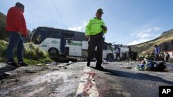 A police officer walks past a Colombian-registered bus that while traveling to Quito crashed in Pifo, Ecuador, Aug. 14, 2018.