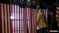 A voter enters a voting booth to fill out a ballot in the U.S. Presidential primary election at the Hale House at Balsams Hotel in Dixville Notch, New Hampshire, Feb. 9, 2016.