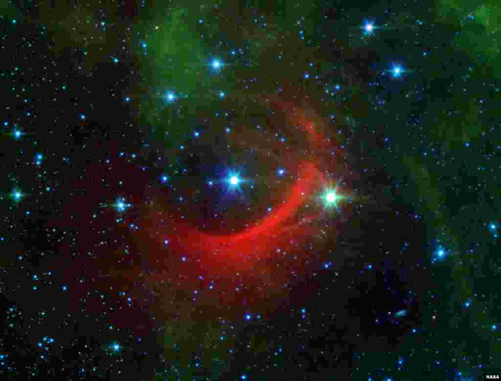 The red arc in this infrared image from NASA&#39;s Spitzer Space Telescope is a giant shock wave, created by a speeding star known as Kappa Cassiopeiae. It is a massive, hot supergiant moving at around 2.5 million mph relative to its neighbors (1,100 kilometers per second). But what really makes the star stand out is the surrounding, streaky red glow of material called a bow shock, in its path. (Image Credit: NASA/JPL-Caltech)