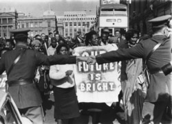 FILE - Police join hands to hold back demonstrators outside court in Pretoria, June 12, 1964 after eight of the accused in the Rivonia Sabotage trial, including Nelson Mandela and Walter Sisulu, were sentenced to life imprisonment.