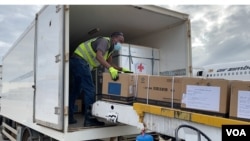 A Zimbabwe health official transfers donated Sinopharm COVID-19 vaccine from a plane from China into a government truck, at Robert Gabriel Mugabe International Airport, Feb. 15, 2021. (Columbus Mavhunga/VOA)