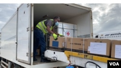 A Zimbabwe health official transfers donated Sinopharm COVID-19 vaccine from a plane from China into a government truck, at Robert Gabriel Mugabe International Airport, Feb. 15, 2021. (Columbus Mavhunga/VOA)