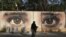 FILE - An Afghan woman waits for transportation in front street art on a barrier wall of the NDS (National Directorate of Security) in Kabul, Afghanistan. 