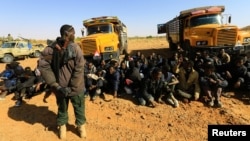 FILE - A member of Sudan's Rapid Support Forces (RSF) stands guard near illegal immigrants and traffickers, who according to the RSF were caught in a remote desert area en route to Libya, in Omdurman, Sudan January 8, 2017. 