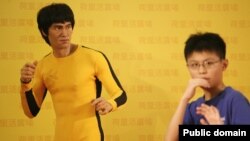 ဟောင်ကောင်က Bruce Lee ရုပ်တုရှေ့မှာ ကလေးငယ်တဦး ဟန်ရေးပြနေပုံ။ (ဇူလိုင်လ ၂၀ ရက်၊ ၂၀၁၃)။