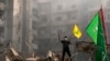 A man flashes the victory sign as holds up a Hezbollah flag while standing on the ruins of his destroyed apartment at the site of an Israeli airstrike in Dahiyeh, Beirut, Lebanon, Nov. 1, 2024. 