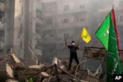 A man flashes the victory sign as he holds up a Hezbollah flag while standing on the ruins of his destroyed apartment at the site of an Israeli airstrike in Dahiyeh, Beirut, Lebanon, on Nov. 1, 2024.