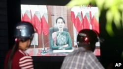 Peoples watch a televised speech by Myanmar's State Counsellor Aung San Suu Kyi, by a roadside, Oct. 12, 2017, in Naypyitaw. 