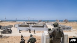 In this picture released by the Israeli army on May 16, 2024, Israeli troops work to connect a U.S.-built floating pier to the shore. The new entry point will allow more humanitarian aid to enter the Gaza Strip.