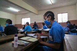 Students wear face masks as a preventive measure against the spread of the COVID-19 coronavirus in their classroom at the Jean Benoit College in Yaoundé, Cameroon, on June 1, 2020.