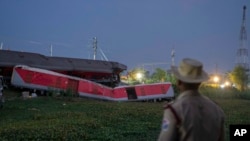 Un policía hace guardia cerca de los restos destrozados de los dos trenes de pasajeros que descarrilaron el viernes en el distrito de Balasore, en el estado oriental de Orissa, India, el 4 de junio de 2023.