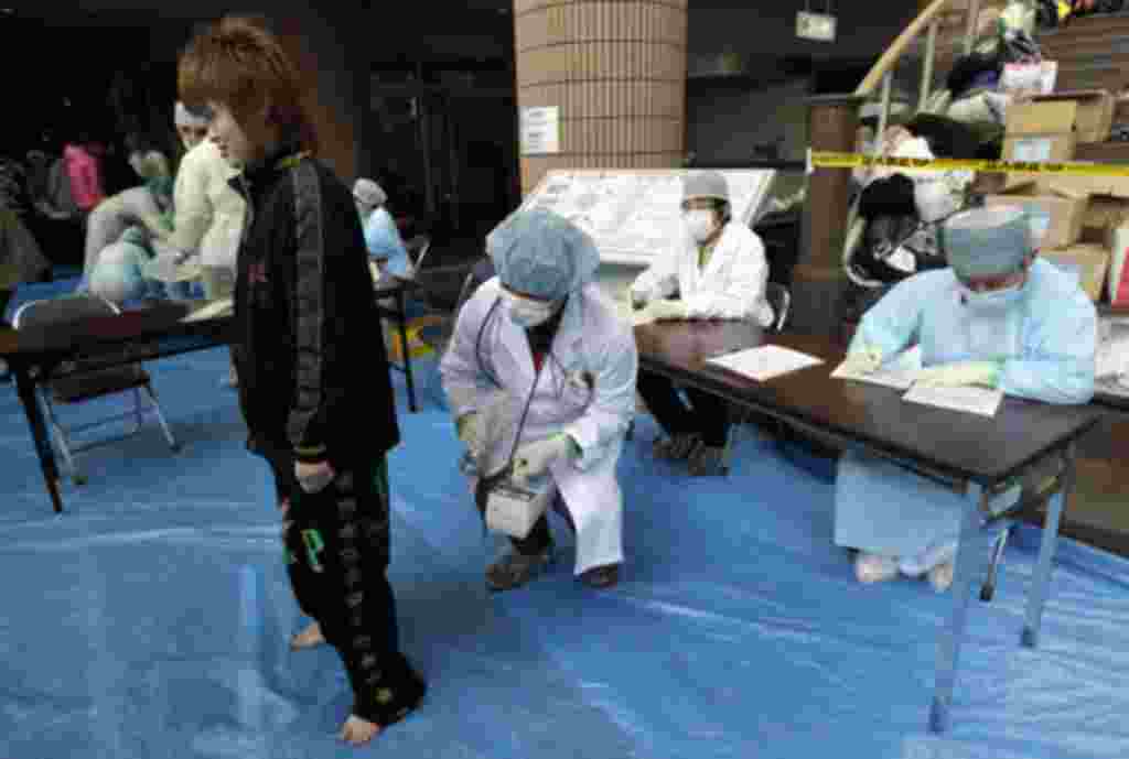 Personal médico examina el nivel de exposición a la radiación de los evacuados.