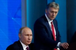 FILE - Kremlin spokesman Dmitry Peskov listens as Russian President Vladimir Putin speaks during annual news conference in Moscow, Russia, Dec. 20, 2018.