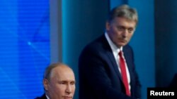 FILE - Kremlin spokesman Dmitry Peskov listens as Russian President Vladimir Putin speaks during annual news conference in Moscow, Russia, Dec. 20, 2018. 