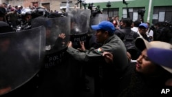 Seguidores del expresidente Evo Morales empujan los escudos de los policías fuera de una comisaría, en La Paz, Bolivia, el jueves 14 de noviembre de 2024, en una protesta contra la detención de dos dirigentes afines al exmandatario. (AP/Juan Karita)